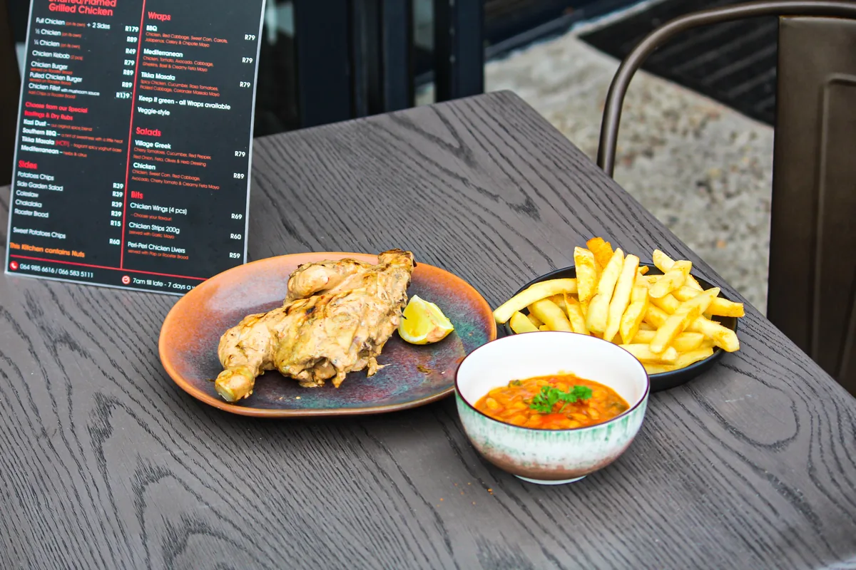 Flame-grilled chicken served with fries, lemon and a side dish.
