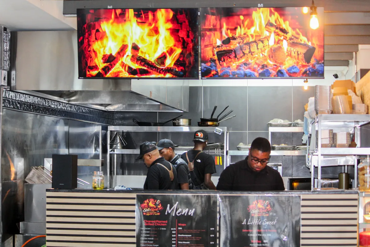 Salt & Roost cooks working beneath the flame displays in the open kitchen.