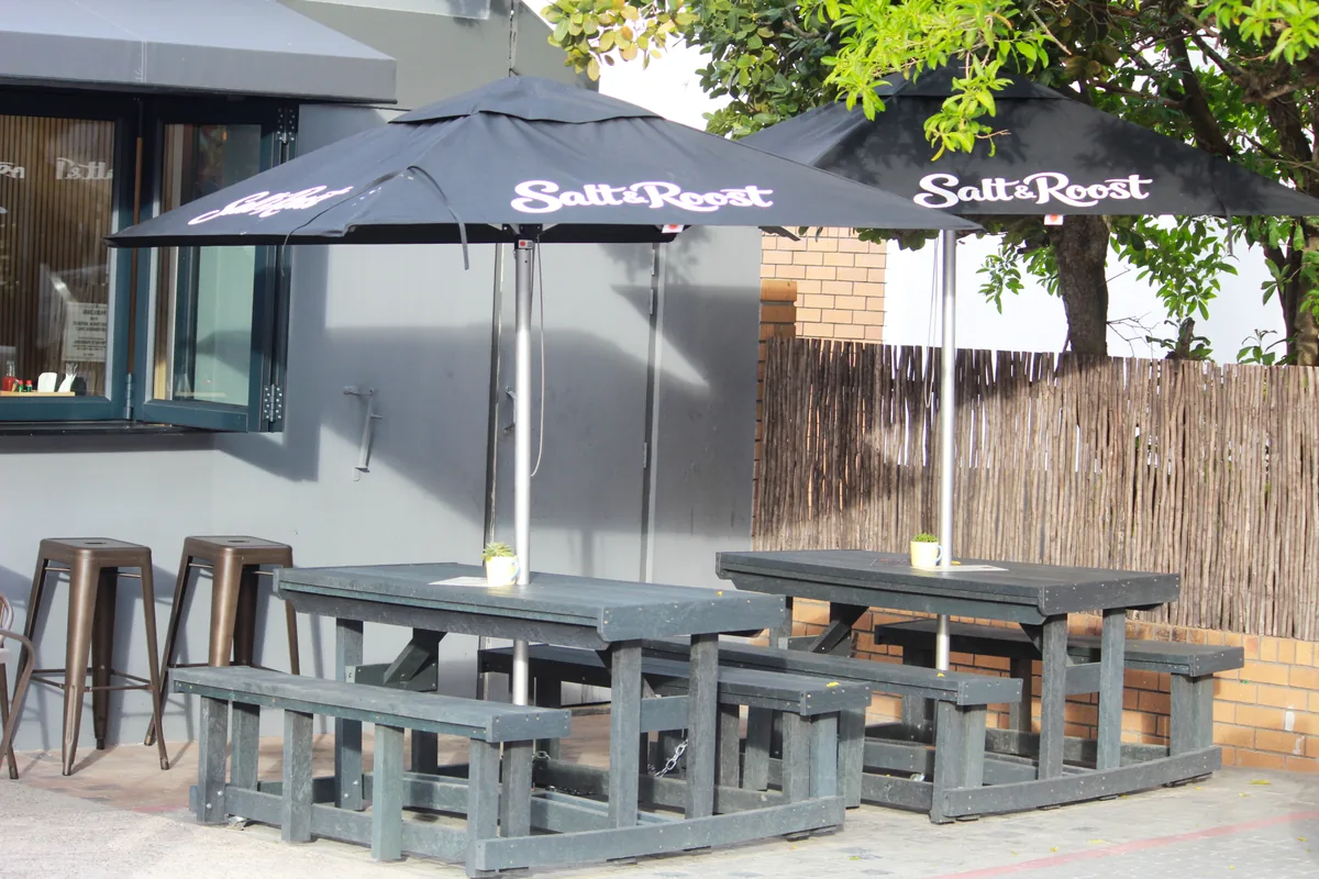 Salt & Roost's shaded outdoor tables and branded umbrellas in Hout Bay.