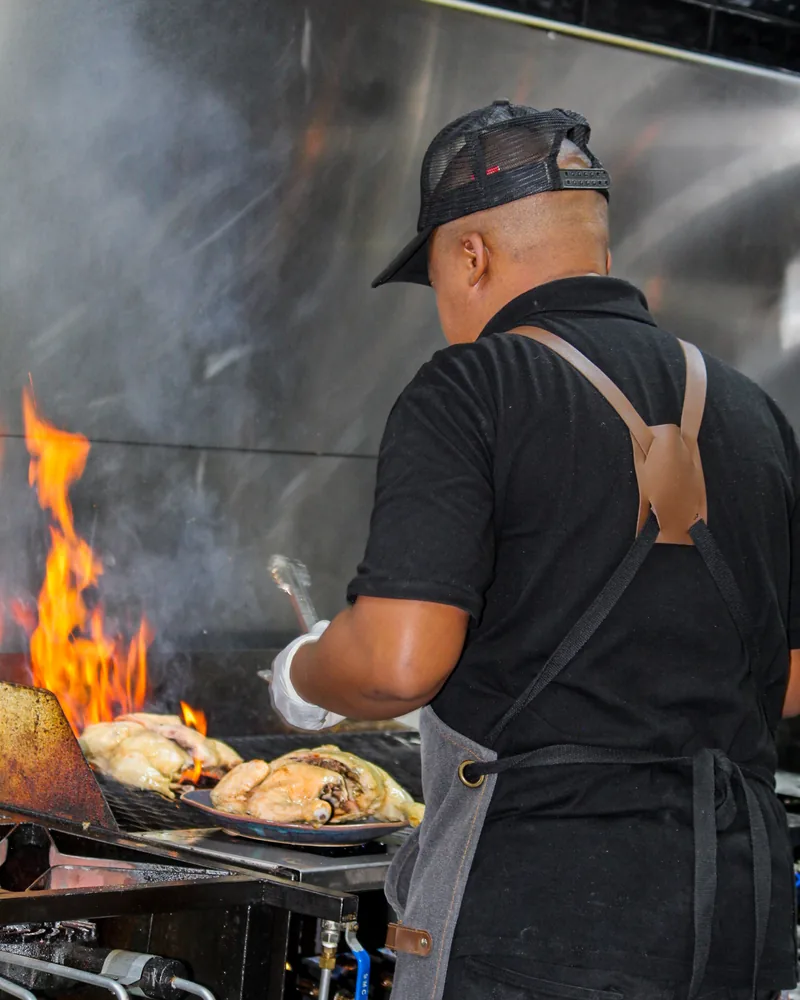 Salt & Roost cook grilling chicken over open flame and smoke.