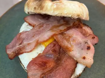 Bacon and fried egg stacked on a rooster brood roll at Salt & Roost.