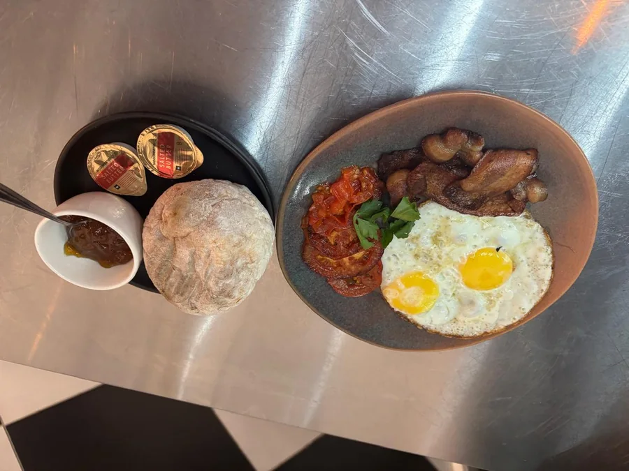 House Breakfast: fried eggs, bacon, grilled tomato and rooster brood with butter and jam.