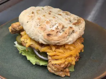 Pulled chicken burger with cheddar, gherkins, red onion and lettuce on rooster brood.
