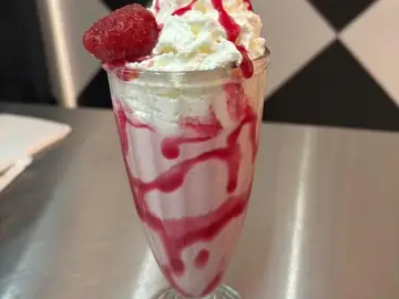 Berry Bliss shake topped with cream, berry syrup and a strawberry.
